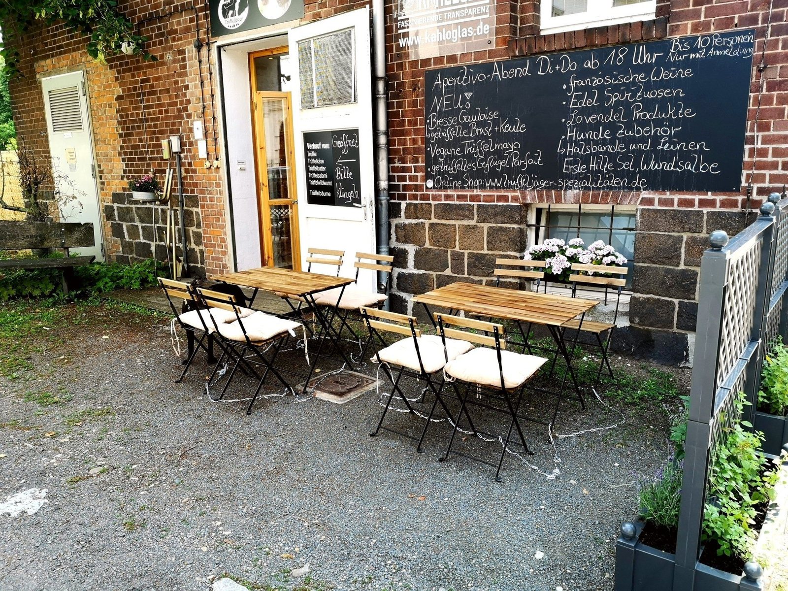 Hofladen von außen mit Tafel und Sitzplätzen vor dem Eingang